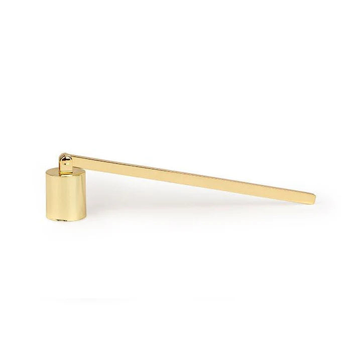 Éteignoir en laiton doré Paddywax posé sur une table avec une bougie, accessoire élégant pour éteindre la flamme sans fumée.